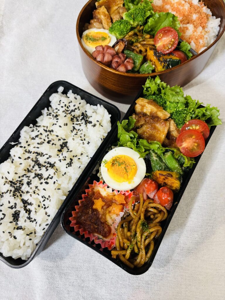 鮭ふりかけご飯とごま塩ご飯に、トンテキ、焼きそば、ゆで卵、かぼちゃ、ブロッコリー、オクラ、ウインナー、ミニトマトを詰めた彩り弁当。五行を意識した風水ランチ。