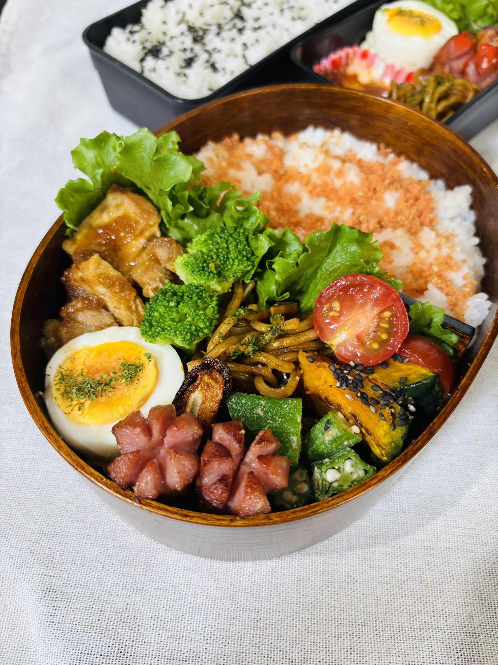 鮭ふりかけご飯にトンテキ、ゆで卵、ウインナー、かぼちゃ、ブロッコリー、オクラ、ミニトマトを詰めた彩り豊かなお弁当。五行のバランスを意識した風水ランチ。